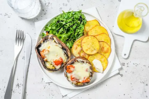 Portobello que es: dos champiñones rellenos de queso y tomate, acompañados de patatas fritas y ensalada.