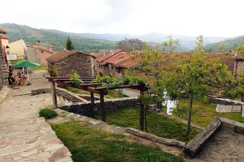Un pintoresco pueblo con casas de piedra y tejados rojos, un camino empedrado y un jardín con enredaderas. La hiruela, un lugar tranquilo.