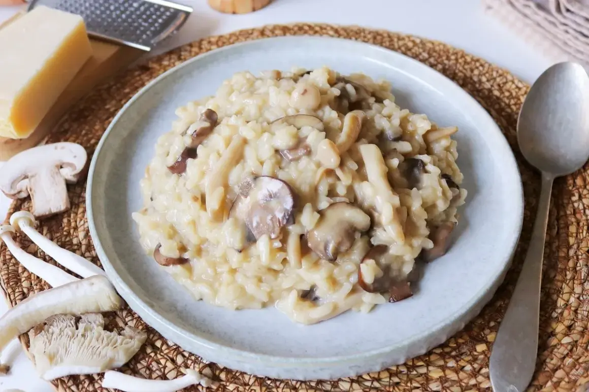 Un cremoso risotto de setas, con champiñones frescos y trozos de queso parmesano rallado al lado.