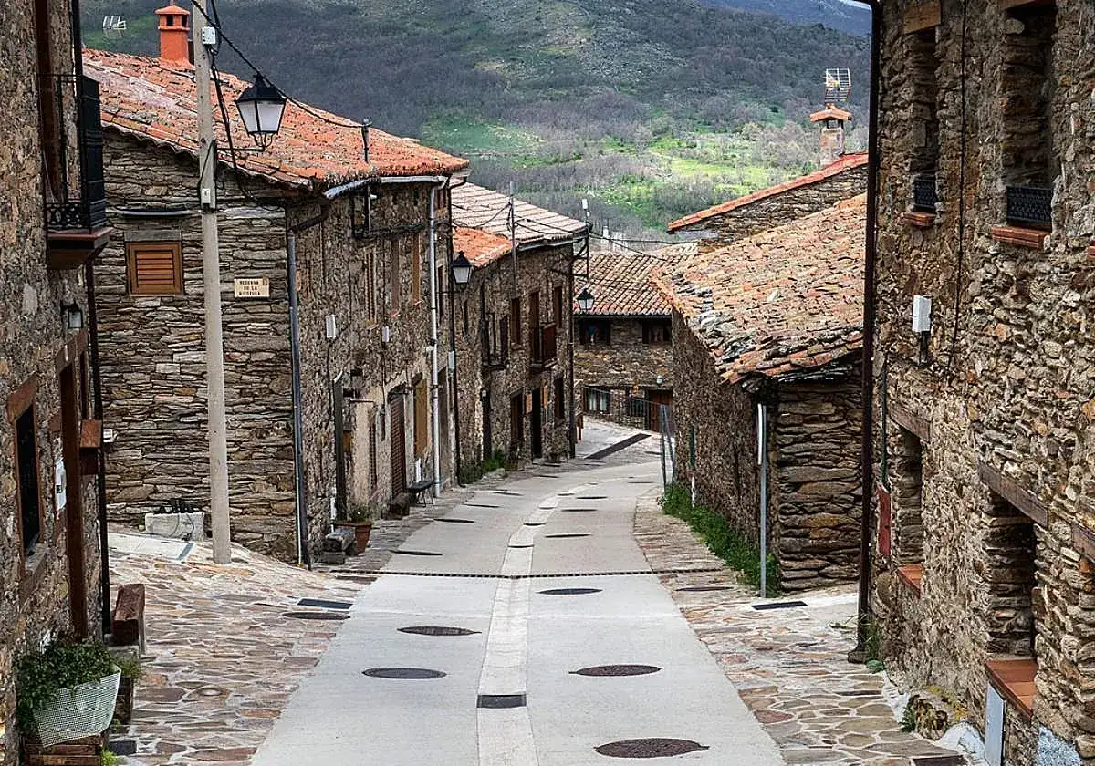 Calle empedrada y casas de piedra con tejados de teja en la hiruela, un pueblo con encanto rural.